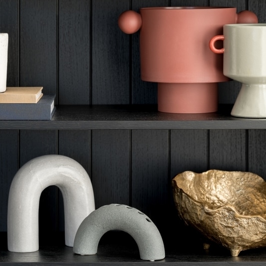 Décoration Étagère Moderne : Vases et Sculptures Design Étagère noire avec vases design, sculptures en arche grises et bol doré texturé pour une déco moderne.