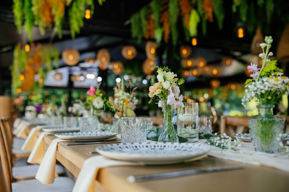 Bouquet de roses et renoncules: l'art du fleuriste Mains d'un fleuriste composant un bouquet de roses, renoncules crème et hortensias roses avec de l'eucalyptus frais sur fond sombre.