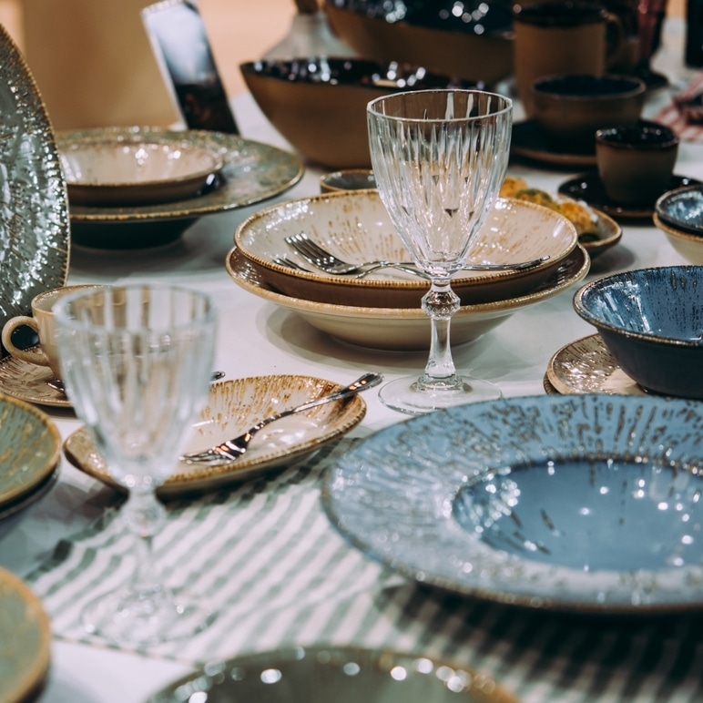 Art de la Table : Vaisselle Artisanale et Verres en Cristal Vaisselle artisanale en céramique et verres en cristal sur une table élégamment dressée.